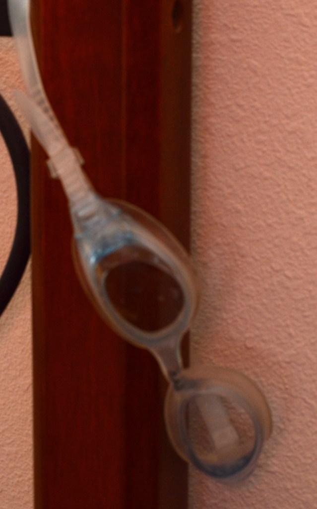 Swim goggles hanging from bedpost.